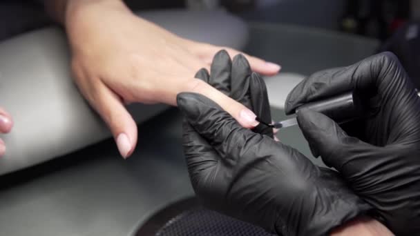 Femme ayant une manucure des ongles dans un salon de beauté avec une vue rapprochée d'un esthéticien appliquant un vernis avec un applicateur . — Video