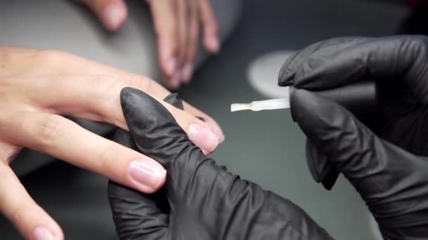 Mujer que tiene una manicura de uñas en un salón de belleza con una vista de cerca de un esteticista aplicando barniz con un aplicador . — Vídeos de Stock