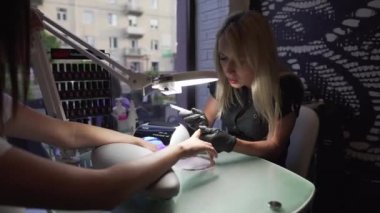 Manikürcü kurtarma yordamı pedikür ve uzantıları üzerinde tırnak salonu kız çivi çivi Tırnak salonu manikür bir güzellik uzmanı tarafından alma içinde closeup çekim bir kadının eller.