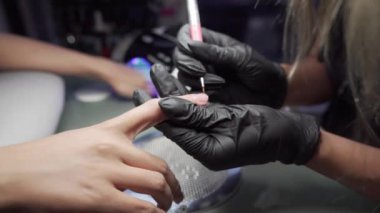 Manikürcü kurtarma yordamı pedikür ve uzantıları üzerinde tırnak salonu kız çivi çivi Tırnak salonu manikür bir güzellik uzmanı tarafından alma içinde closeup çekim bir kadının eller.
