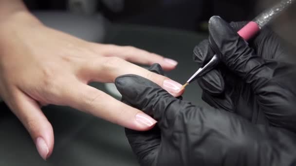 The manicurist makes pedicure procedure of recovery and nail extensions on the nails of the girl in the nail salon . Closeup shot of a woman hands in nail salon receiving a manicure by a beautician. — Stock Video