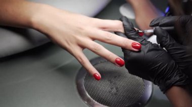 Güzellik Salonu bir aplikatör ile vernik uygulama bir güzellik closeup manzaralı manikür çivi olan bir kadın. Tırnak oje ile boyalı Master. Kırmızı tırnak el kadeh ayrıntıları.