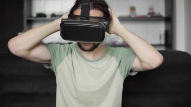 Genç onun Vr kulaklık ekran sanal gerçeklik oyunu için kullanma veya evde oturma odasında kanepede otururken 360 video izlerken hipster adam başlangıç sakallı. VR teknolojisi.