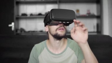 Sanal gerçeklik oyunu için onun Vr kulaklık ekran kullanan yenilikçi adam Genç sakallı veya 360 video izlerken ve bir şey dokunmak çalışırken gördü kanepede otururken. VR teknolojisi.