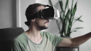 Sanal gerçeklik oyunu için onun Vr kulaklık ekran kullanan yenilikçi adam Genç sakallı veya 360 video izlerken ve bir şey dokunmak çalışırken gördü kanepede otururken. VR teknolojisi.