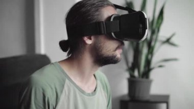 Genç sakallı onun Vr kulaklık ekran sanal gerçeklik oyunu için kullanma veya 360 video izlerken hipster adam ve ve bir şey tarafından evde oturma odasında kanepede otururken korkmuş yapıldı..