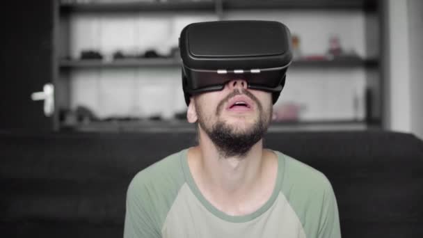 Νέος γένια hipster άνθρωπος έναρξη χρησιμοποιώντας οθόνη του Vr ακουστικά με ακουστικά για παιχνίδι εικονικής πραγματικότητας ή βλέποντας το 360 βίντεο και γοητευμένος και έκπληκτος από κάτι. — Αρχείο Βίντεο