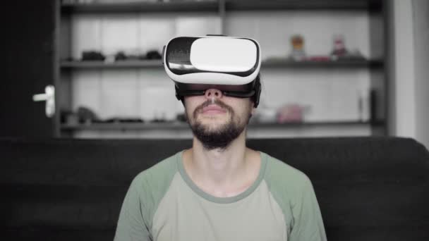 Junge bärtige Hipster-Mann beginnen mit seinem vr Headset-Display mit Kopfhörern für Virtual-Reality-Spiel oder sehen das 360-Video, während sie auf dem Sofa zu Hause im Wohnzimmer sitzen. vr-Technologie. — Stockvideo