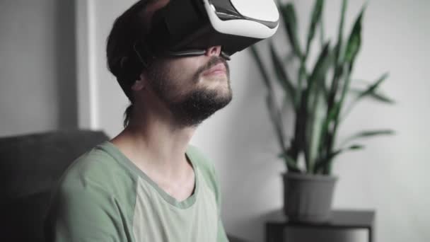 Young bebaarde hipster man met zijn Vr headset display voor virtuele werkelijkheid spel of kijken naar de 360 video, en proberen aan te raken om iets te zien hij zittend op de Bank. Vr-technologie. — Stockvideo