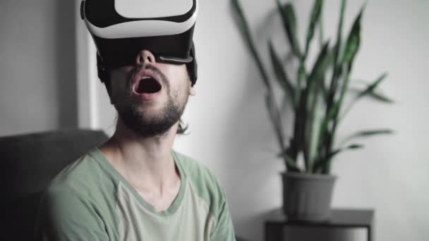 Joven hombre hipster barbudo empezar a usar su pantalla de auriculares VR con auriculares para el juego de realidad virtual o ver el video 360 y cautivado y sorprendido por algo . — Vídeo de stock