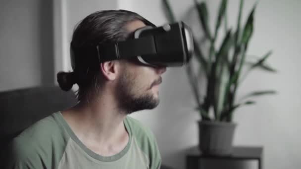 Feliz joven barbudo hipster hombre utilizando su pantalla de auriculares VR para el juego de realidad virtual o ver el video 360 mientras está sentado en el sofá en casa en la sala de estar. Tecnología VR . — Vídeos de Stock