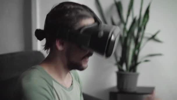 Νέοι γενειοφόρος άνδρας hipster χρησιμοποιώντας την οθόνη ακουστικό Vr για να παρακολουθείτε βίντεο 360 και αισθάνεται όπως ο ίδιος είναι σε μια συναυλία ή ντίσκο ενώ κάθεστε στον καναπέ στο σπίτι στο σαλόνι. Τεχνολογία VR. — Αρχείο Βίντεο