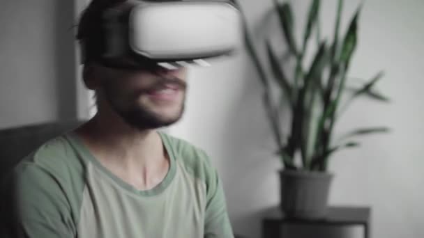 Junger bärtiger Hipstermann mit seinem vr-Headset-Display, um das 360-Video anzusehen und fühlt sich wie auf einem Konzert oder in einer Disco, während er zu Hause auf dem Sofa im Wohnzimmer sitzt. vr-Technologie. — Stockvideo