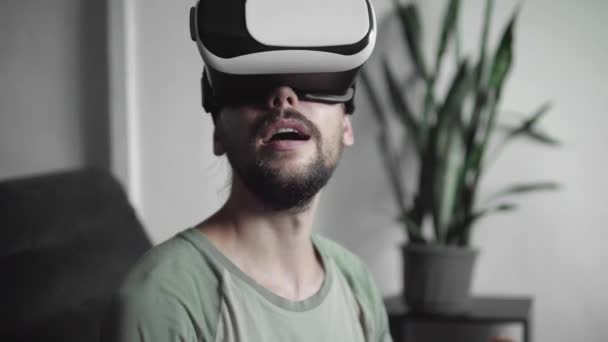 Young bebaarde hipster man zijn Vr headset weergave te gebruiken voor de virtuele werkelijkheid spel of kijken naar de 360 video en proberen te raken iets hij zien en vangen zittend op de Bank. Vr-technologie. — Stockvideo