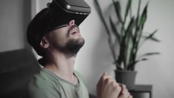 Mladý vousatý bokovky člověka pomocí jeho Vr headset pro virtuální reality hry nebo sledovat 360 video a snaží zahnat to, co vidí, zatímco sedí na pohovce. VR technologie. — Stock video