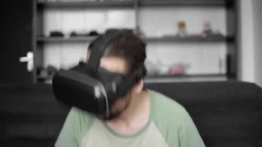 Genç sakallı 360 video ve bir duygu olarak o bir konser izlemek için onun Vr kulaklık görüntü kullanılarak hipster adam ya da evde oturma odasında kanepede otururken disko. VR teknolojisi.