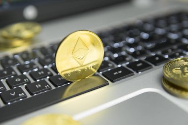 Altın Ethereum madeni para ile altın gümüş laptop ve diyagram grafik grafik arka plan olarak bir ekranda siyah klavyesindeki etrafında yalan. Ethereums online iş araştırma. Ticaret.
