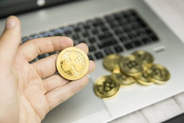 Laptop klavye ve altın sikke yığını bir arka plan dalgalanma para tutan erkek işadamı el. Sanal para ve finansal büyüme kavramı. Of Ripples ticaret madencilik.