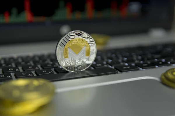 Moneda de oro Monero con monedas de oro en torno a un teclado negro de la computadora portátil de plata y diagrama gráfico en una pantalla como fondo. Minería de Moneros negocio en línea. Operaciones . — Foto de Stock