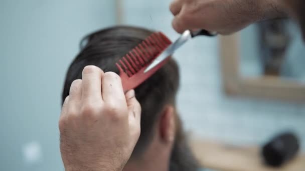 Close-up van Kapper snijdt het haar door schaar op barbershop. Kappers handen op werkproces. Kapper maken kapsel van aantrekkelijke bebaarde man in de kapsalon. Kapper op het werk. Beauty Salon. — Stockvideo