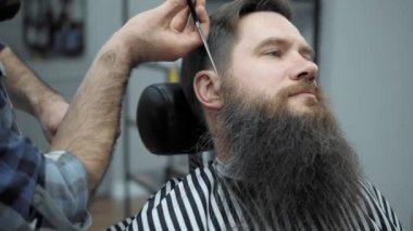 Yapıyor Kuaför saç kesimi ile yetişkin erkekler erkek kuaför salonu içinde uzun sakallı sakallar. Sakal bakım. Salonların işyerinde. Sakal saç şekillendirme ve kanununu bir kuaför dükkanında.
