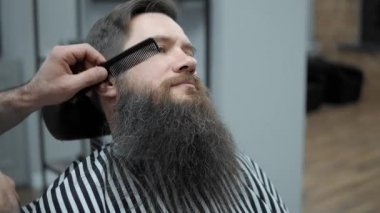 Yapıyor Kuaför saç kesimi ile yetişkin erkekler erkek kuaför salonu içinde uzun sakallı sakallar. Sakal bakım. Salonların işyerinde. Sakal saç şekillendirme ve kanununu bir kuaför dükkanında.