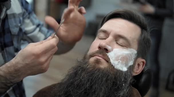 理发师剃胡子的男子与直剃刀刀片在 s 美发沙龙或理发店。理发和剃须在美发店, 理发店和剃须沙龙. — 图库视频影像