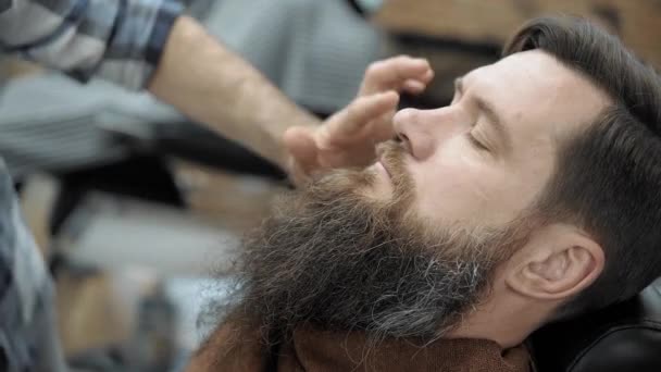 Barbiere radere gli uomini con una lunga barba con lama rasoio dritto in s parrucchiere o barbiere. Mans taglio di capelli e rasatura dal parrucchiere, barbiere e salone da barba . — Video Stock