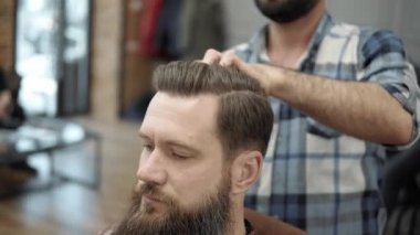 Stil uzun sakallı yakışıklı bir adamla yapıyor Kuaför Close-up. Çalışma süreci salonların ellere. Berber dükkanı çekici sakallı adamın yapma saç kesimi berber. Kuaför iş başında.