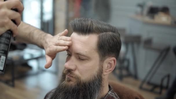 Primer plano de peluquero haciendo estilo con un hombre guapo con una barba larga. Peluqueros manos en el proceso de trabajo. Peluquero haciendo corte de pelo de hombre barbudo atractivo en la barbería. Peluquería en el trabajo . — Vídeos de Stock