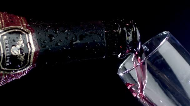 Red wine being poured into a glass of black background. Slow motion — Stock Video