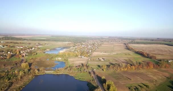 Вид на летнюю сельскую местность с сельскохозяйственными полями и домами. Фермерский участок в сельской местности с домами и строительными крышами. Вид с высоты птичьего полёта . — стоковое видео