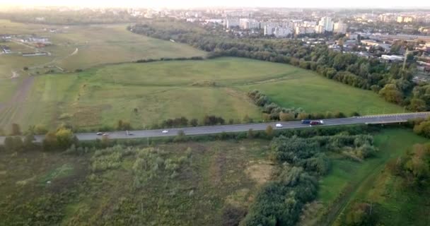 Widok z lotu ptaka ciężarówki i innego ruchu, jazdy wzdłuż drogi o wschodzie słońca. Piękny zachód słońca nad drogą pełne ruchu i rzeka. Wielkie nieba. Pięknej jesieni. Colorful natura — Wideo stockowe