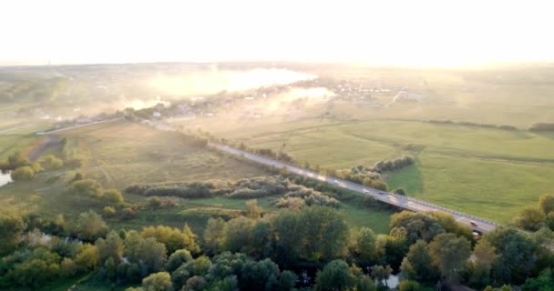 Aerial view of a truck and other traffic driving along a road at sunrise. Beautiful sunset over the road full of traffic and long river. Great skies. Beautiful autumn. Colorful nature — Stock Video