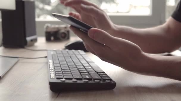 Young man using tablet while sitting computer keyboard and mouse. Freelancer photographer working and using tablet for communication with clients. — Stock Video