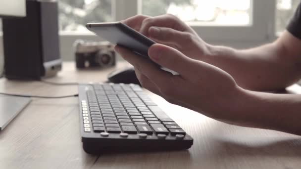 Young man using tablet while sitting computer keyboard and mouse. Freelancer photographer working and using tablet for communication with clients. — Stock Video