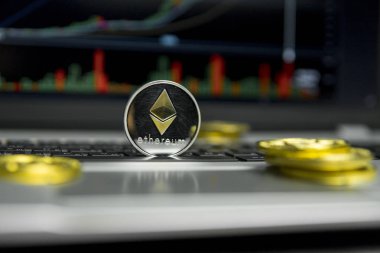 Altın Gümüş Ethereum madeni para ile altın gümüş laptop ve diyagram grafik grafik arka plan olarak bir ekranda siyah klavyesindeki etrafında yalan. Ethereums online iş araştırma. Ticaret.