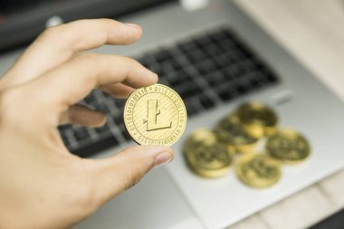 Litecoin para laptop klavye ve altın sikke yığını bir arka planda tutan erkek işadamı el. Sanal para ve finansal büyüme kavramı. Ticaret, araştırma Litecoin paraları.
