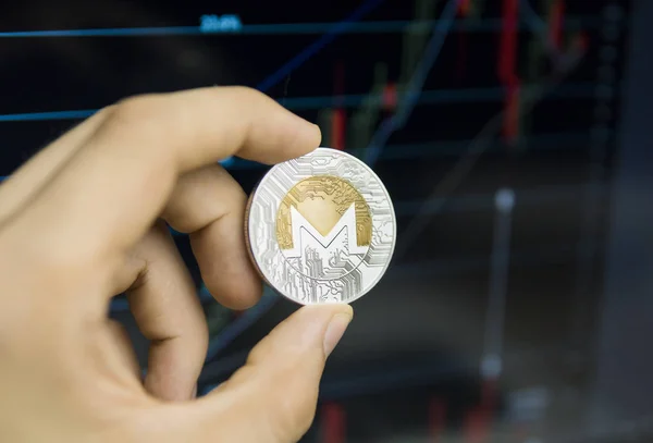 Hombre de negocios mano sosteniendo moneda Monero en un fondo de gráfico de crecimiento en una pantalla de ordenador portátil. Dinero virtual y concepto de crecimiento financiero en el fondo del gráfico. Comercio Minería de monedas de moneros . — Foto de Stock