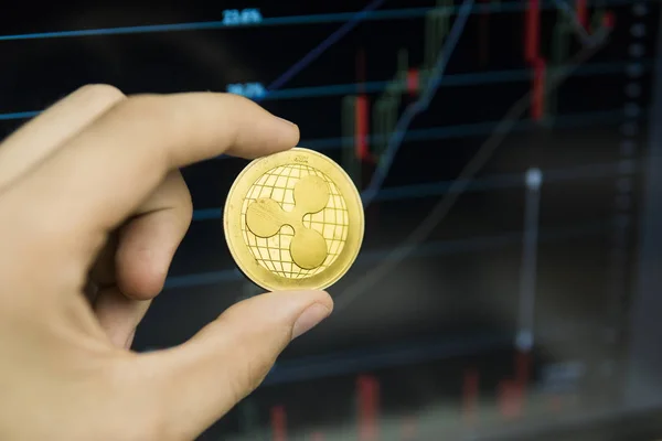 Male businessman hand holding Ripple coin on a background of growth graph on a screen of laptop. Virtual money and Financial growth concept on chart background. Trading Mining of Ripples. — Stock Photo, Image