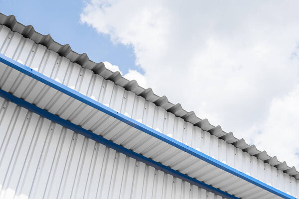 Industrial construction of Metal white sheet and blue corners. Roof sheet metal or corrugated roofs of factory building or warehouse