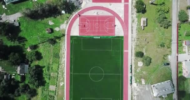 Boş spor Bahçesi stadyum kuş bakışı görünüme üzerinden. Kırmızı spor büyük tenis ve basketbol oynamak için zemin. Futbol futbol sahası yeşil ve yollar çalıştıran. — Stok video