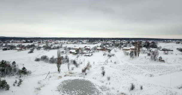 Замерзший пруд, покрытый снегом, и растения, покрытые снегом возле деревни. Зимний пейзаж . — стоковое видео