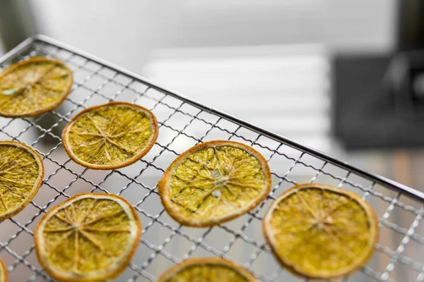 Rodajas de naranja enlatadas en rejilla para secar. Frutas secas que se pueden utilizar como decoración para la comida o cócteles. Alimento vegetariano saludable rico en vitaminas y microelementos . — Foto de Stock