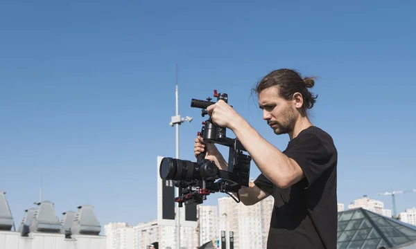 Vidéographe professionnel tenant la caméra sur cardan 3 axes. Vidéaste utilisant le stéadicam. L'équipement Pro aide à faire des vidéos de haute qualité sans trembler . — Photo