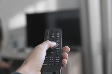 Oturma odasında televizyon arka plan uzaktan kumandayla tutan el.