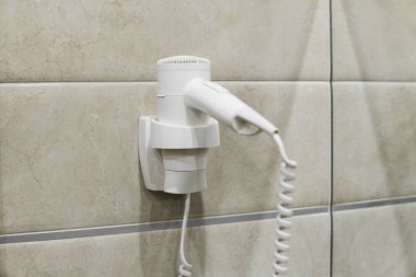 Banyodaki duvarda beyaz saç kurutma makinesi var. SPA.