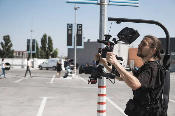 Professionele videograaf vasthouden van de camera op 3-axis gimbal die gemonteerd op gemakkelijk tuig. Videograaf gebruiken steadicam. Pro apparatuur helpt om hoge kwaliteit video zonder schudden. — Stockfoto