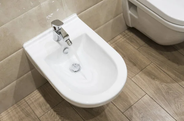 Rincian bidet keramik putih dengan air mengalir di kamar mandi modern . — Stok Foto