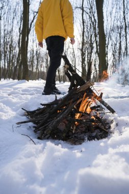 Kış Orman ayakta yakınındaki küçük bir yangın sarı ceketli genç adam.